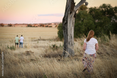 People walking through long dry grass at sunset