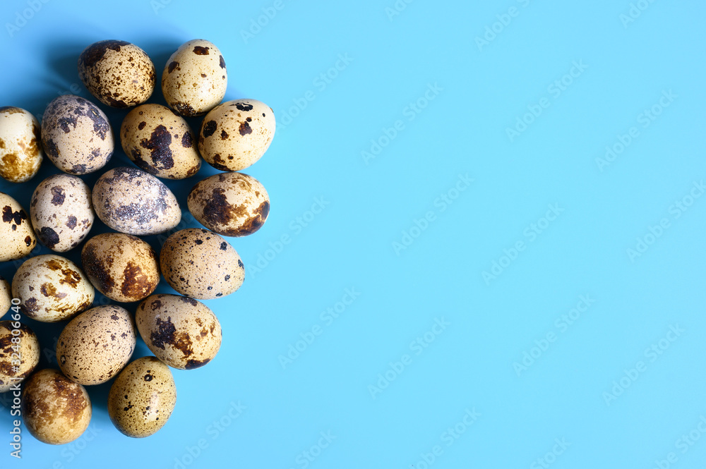 pile of quail eggs on a blue background. space for text