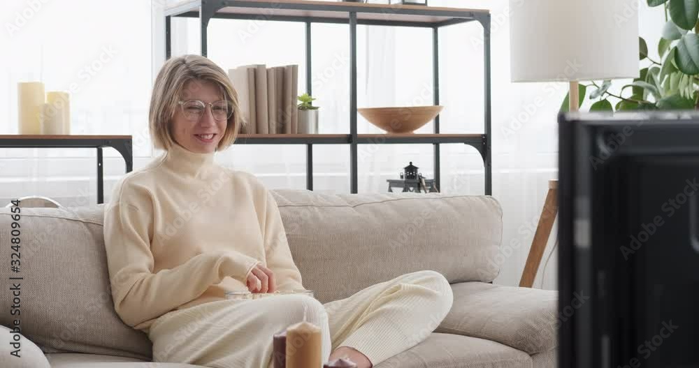Woman laughing while watching tv and eating popcorn at home Woman laughing while watching tv and eating popcorn at home
