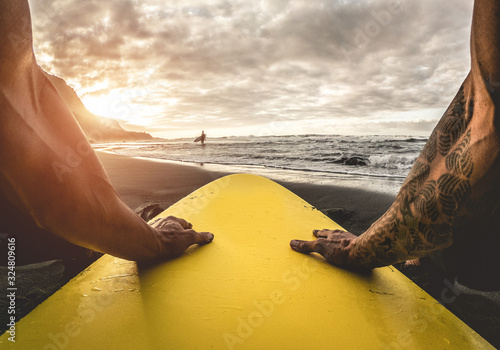 Pov view of tattoo surfer waiting waves on tropical beach - Fit atlhete having fun doing extreme water sports - Travel and healthy lifestyle concept - Focus on hands