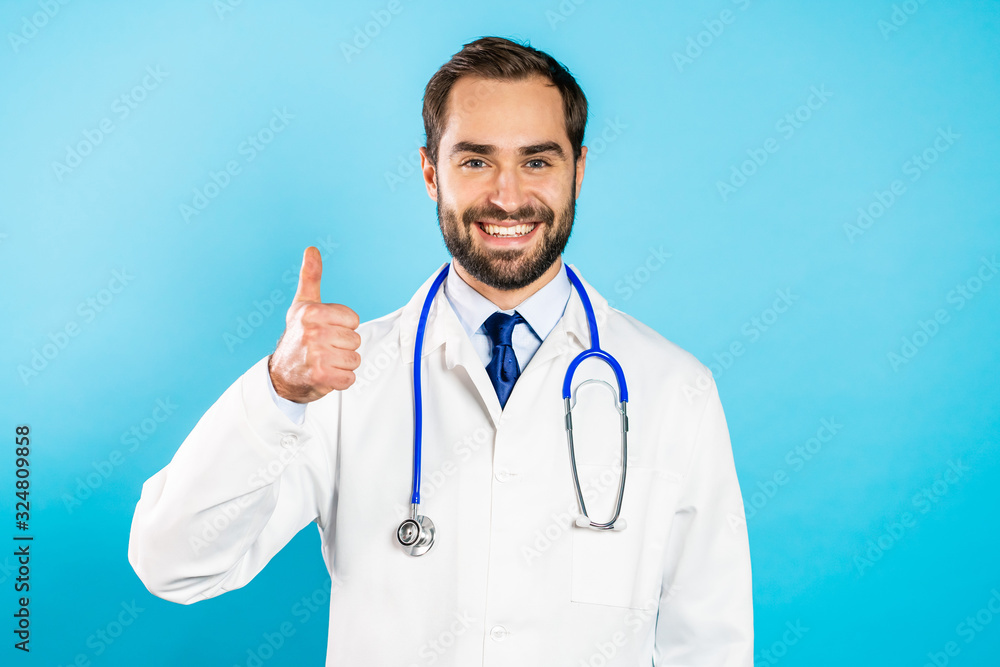 Portrait of smiling positive doctor in professional medical white coat showing thumbs up gesture. Doc isolated on blue background. Portrait of smiling positive doctor in professional medical white coat showing thumbs up gesture. Doc isolated on blue background.