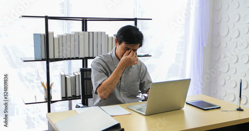 A senior Asian man using notebook for working and businesswoman serious about the work done until the headache