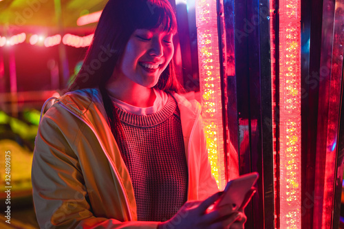 Valokuva Happy asian girl using smartphone at amusement park - Young trendy woman having