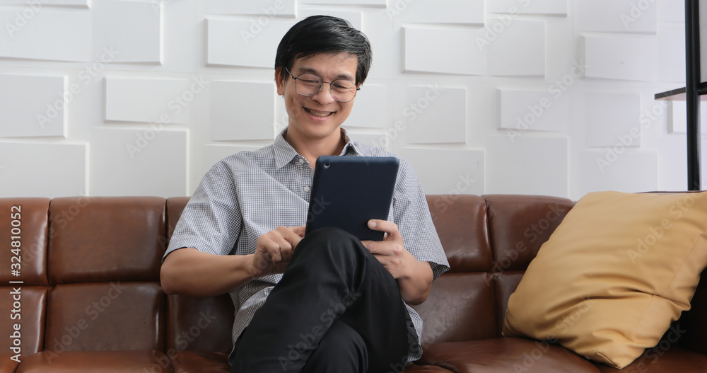 Senior Asian man playing tablet and video call on sofa in living room at home Portrait of Asian elderly man is Relaxing and Happiness With playing tablet Senior Asian man playing tablet and video call on sofa in living room at home Portrait of Asian elderly man is Relaxing and Happiness With playing tablet