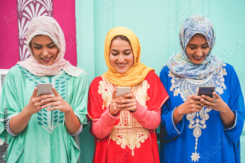 Happy arabian friends using smartphones outdoor - Focus on faces