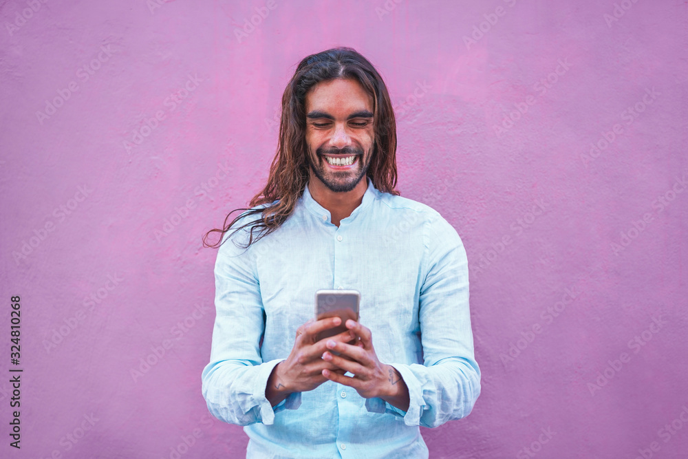 Handsome man in casual clothes  using a smartphone app with purple wall in background - Focus on his face