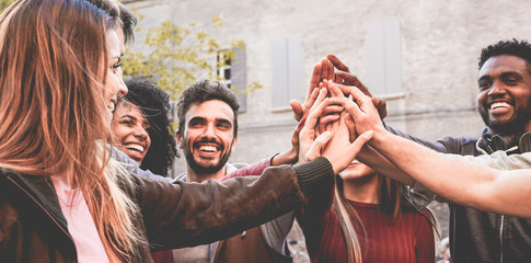 Young happy people stacking hands outdoor - Diverse culture students celebrating together - Youth lifestyle, university, relationship, human resorces, work and friendship concept - Focus on hands