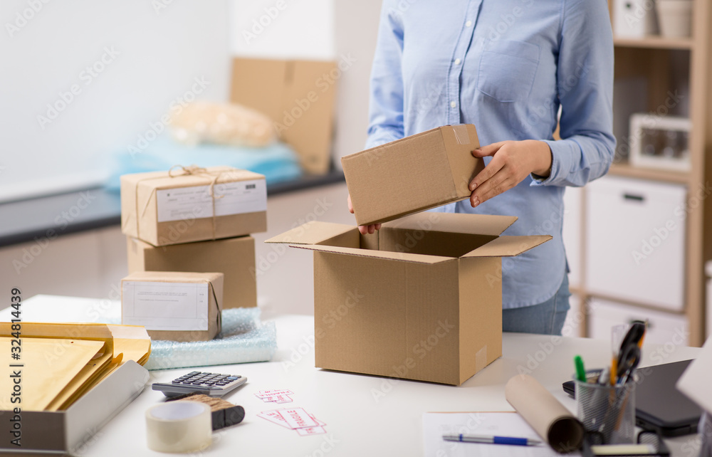 delivery, mail service, people and shipment concept - close up of woman packing parcel box at post office delivery, mail service, people and shipment concept - close up of woman packing parcel box at post office