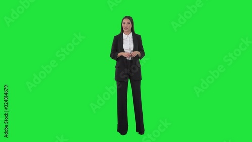 Elegant business woman in suit talking and advertising during presentation. Full length on green screen background.