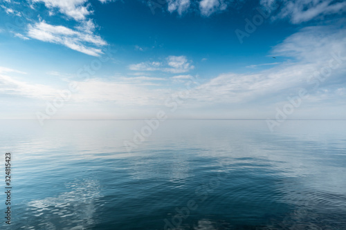 Beautiful white clouds on blue sky over calm sea with sunlight reflection, Harmony of calm water surface. © Tommaso Lizzul