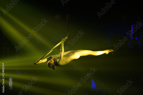 Flexible young woman make performance on aerial hoop, yellow light, flexible split on aerial hoop, aerial circus show