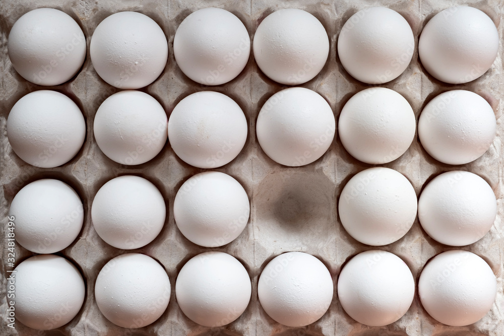 White chicken eggs in a cardboard box with one empty space, background. White chicken eggs in a cardboard box with one empty space, background.