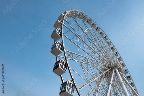 Modern ferris wheel on a blue sky background. Huge ferris wheel with cabins.
