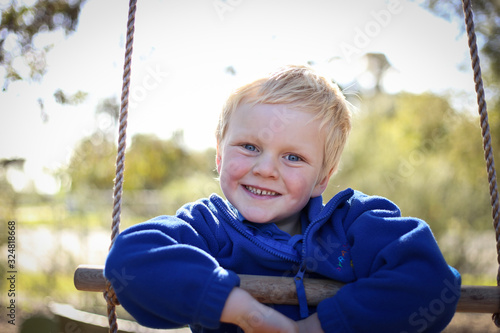 Happy preschool age boy playing on rope ladder at kindergarten 