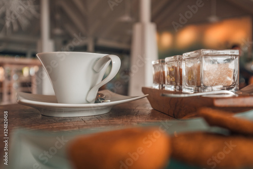 Cup of coffee on wooden table with selection of sugar and cookies