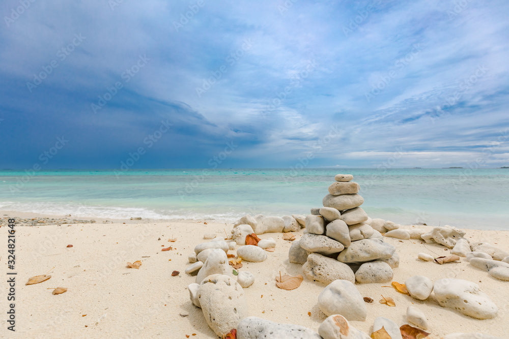 Folded pyramid Zen pebble stones on the sea beach at dramatic sky