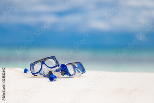 Diving goggles and snorkel gear near beach on blurred sea background