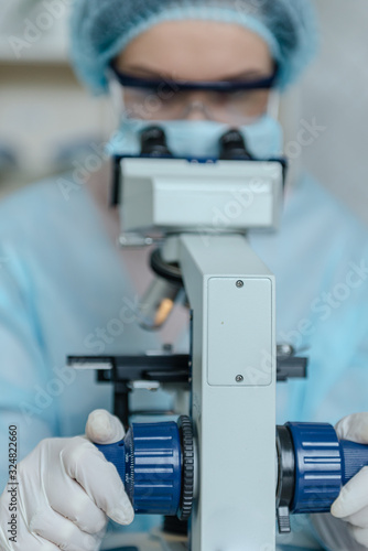Female scientist studying coronavirus. The doctor looks through a microscope at a vaccine against coronavirus.