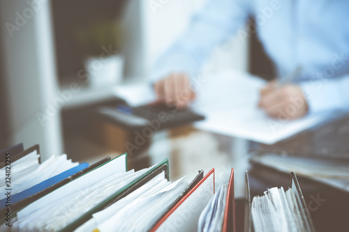 Binders of papers waiting to process by bookkeeper woman or financial inspector, close-up. Business portrait. Audit or tax concepts photo