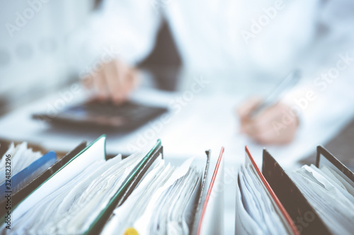 Bild auf Leinwand Binders of papers waiting to process by bookkeeper woman or financial inspector, close-up