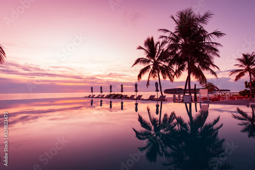 Beautiful poolside and sunset sky. Luxurious tropical beach landscape, deck chairs and loungers and water reflection over the swimming pool. Luxury summer vacation or holiday, hotel resort © icemanphotos