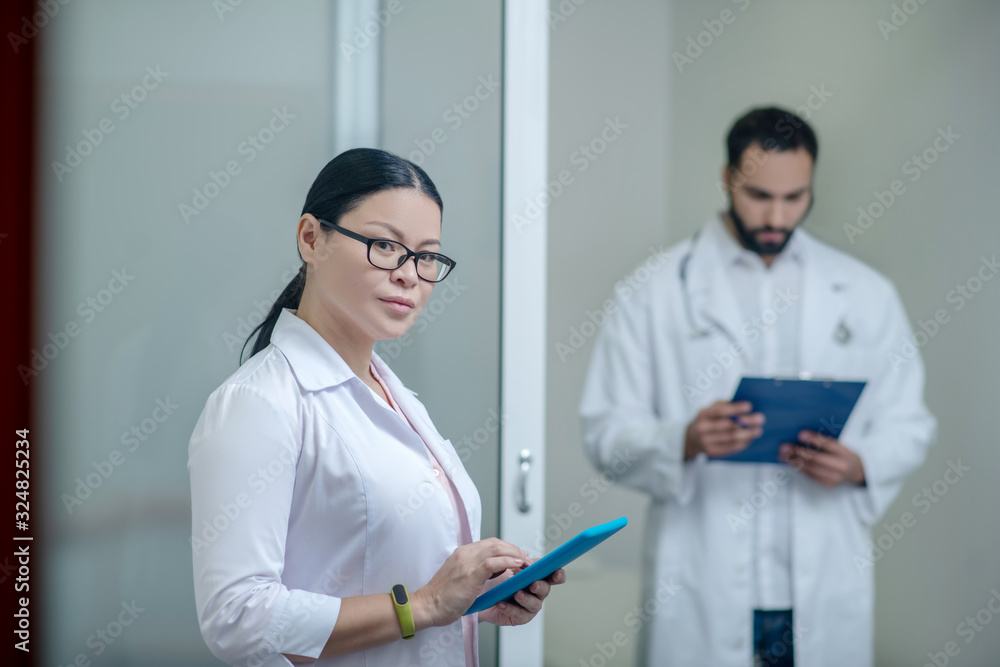 Dark-haired male and female doctors reading notes