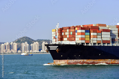 Large cargo container ship, fully loaded with boxes is departing from sea port , she is beginning an international voyage. View on the forward part of the vessel. 