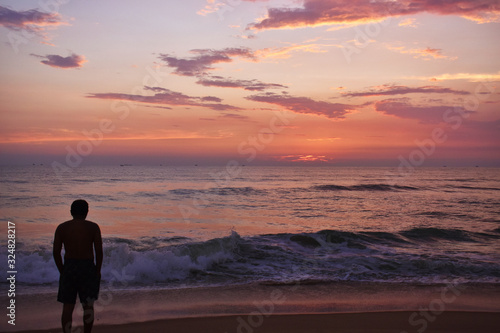 a man standing in a beach during the sunset in ocean in Goa