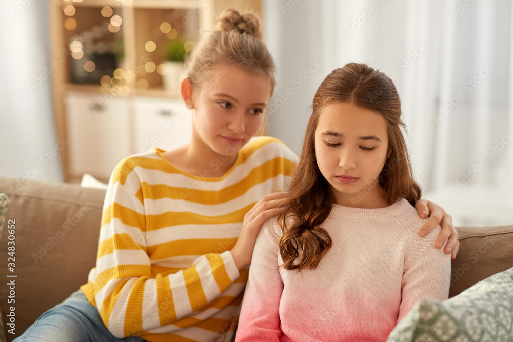 friendship, support and people concept - teenage girl comforting her sad friend at home