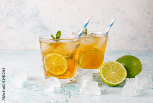 Iced tea with lime and ice on light background