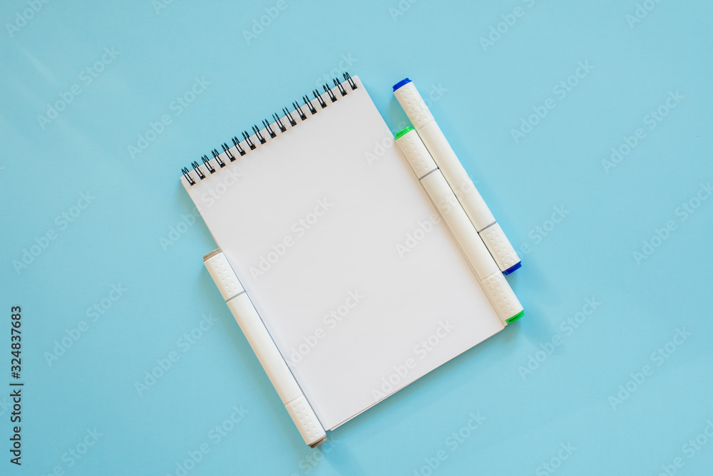 Notepad and sketch markers on a blue background Notepad and sketch markers on a blue background