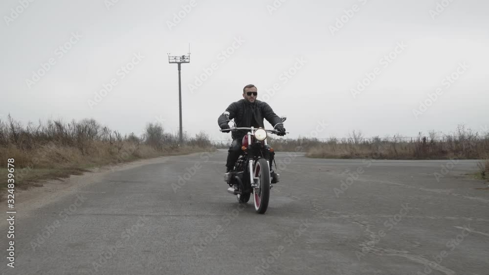 View of brutal biker in sunglasses riding on motorcycle on the highway View of brutal biker in sunglasses riding on motorcycle on the highway