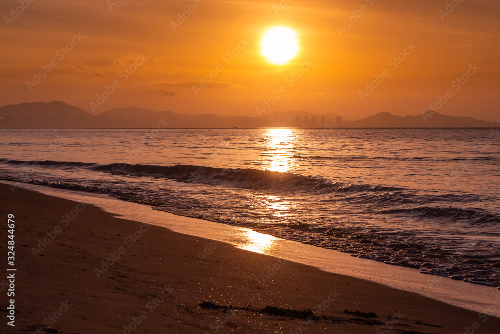 Beautiful orange sunrise is on the beach by the sea
