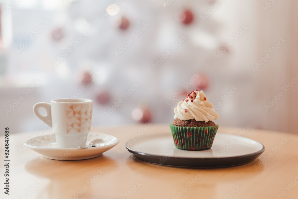 Italian coffee Cup and cupcake on the table near the Christmas tree with white bokeh Italian coffee Cup and cupcake on the table near the Christmas tree with white bokeh