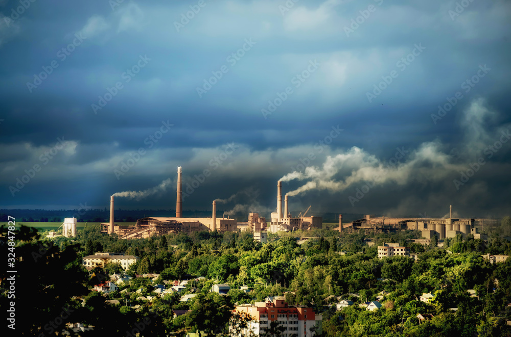 View of an industrial facility located in a residential area with many smoking chimneys. Ecological problems of environmental pollution View of an industrial facility located in a residential area with many smoking chimneys. Ecological problems of environmental pollution