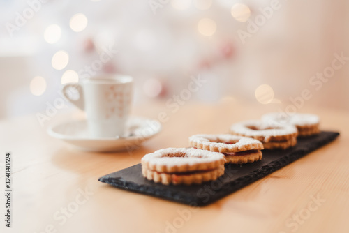 Italian coffee small Cup and cookie on the table near the Christmas tree with golden bokeh