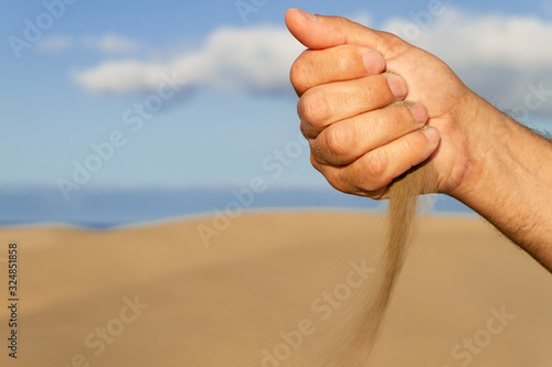 Man hand leaking sand on the a beach