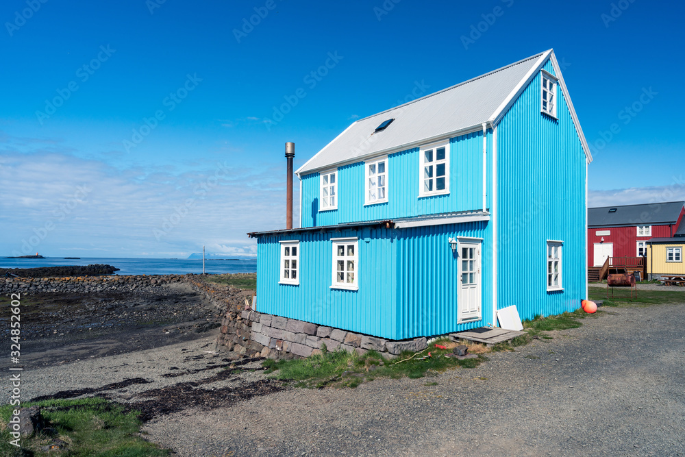 Colorful blue and red buildings in the charming city of Flatey Island in Iceland just outside Stykkisholmur and the Westfjords. Blue sky and sunny weather. Architecture and visit concept Colorful blue and red buildings in the charming city of Flatey Island in Iceland just outside Stykkisholmur and the Westfjords. Blue sky and sunny weather. Architecture and visit concept