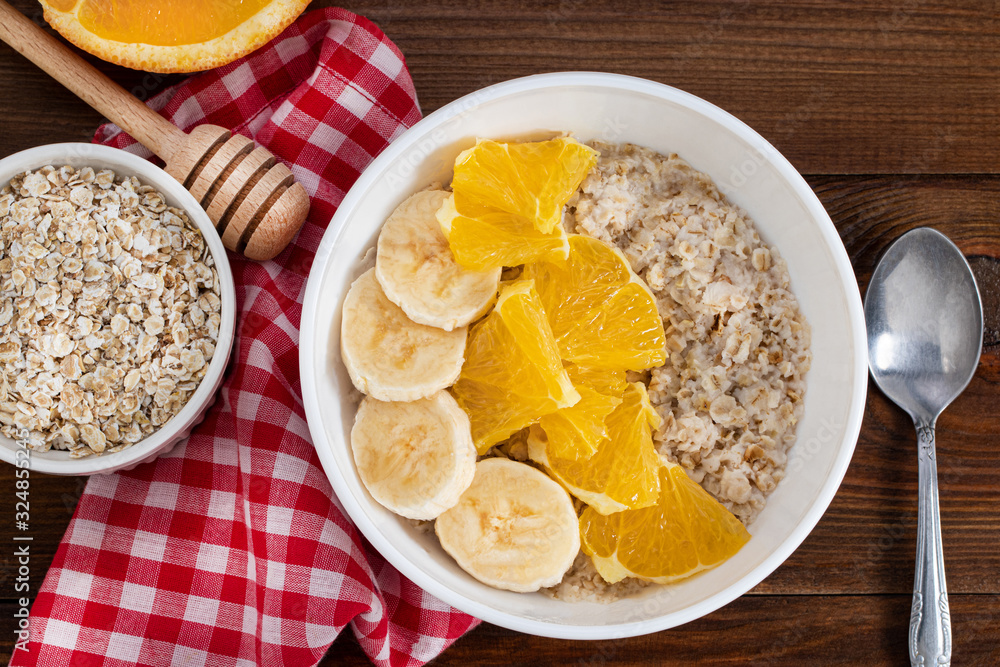 Bowl of oatmeal porridge with banana and orange on wooden background. Top view, copy space Bowl of oatmeal porridge with banana and orange on wooden background. Top view, copy space