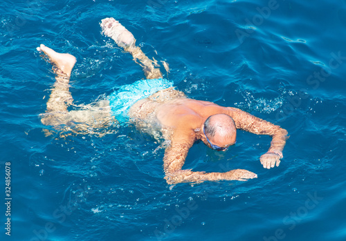 A man swims in the blue water of the sea