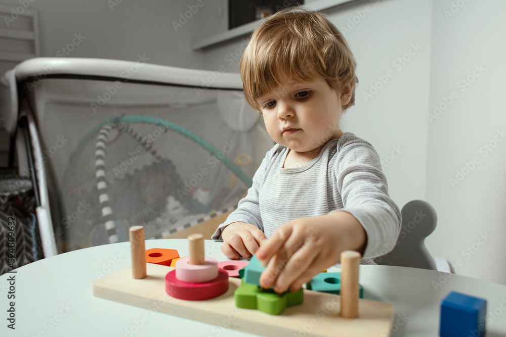Beautiful toddler play with a wooden toys at home. Toddler play with a color educational toy. Child play at the table in the baby room. Child development. Funny baby. Lifestyle. Beautiful toddler play with a wooden toys at home. Toddler play with a color educational toy. Child play at the table in the baby room. Child development. Funny baby. Lifestyle.