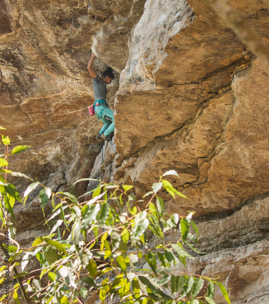 Strong fit woman rock climbing up high