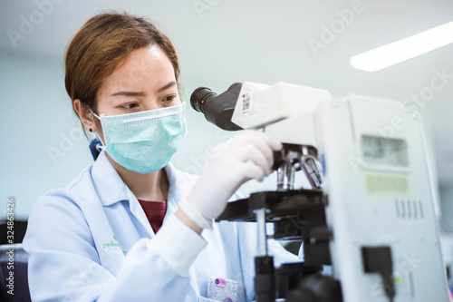 medical technician look at the microscope  in medical laboratory