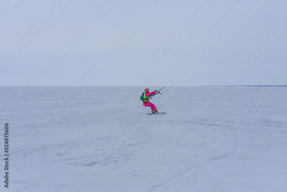 Naklejka premium Kite surfer ride on snowboard. Snowkiting in the snow on frozen lake.