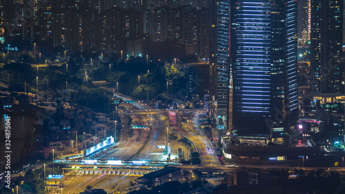 Photography Hong Kong city skyline timelapse at night with Victoria Harbor and skyscrapers illuminated by lights over water viewed from mountain top