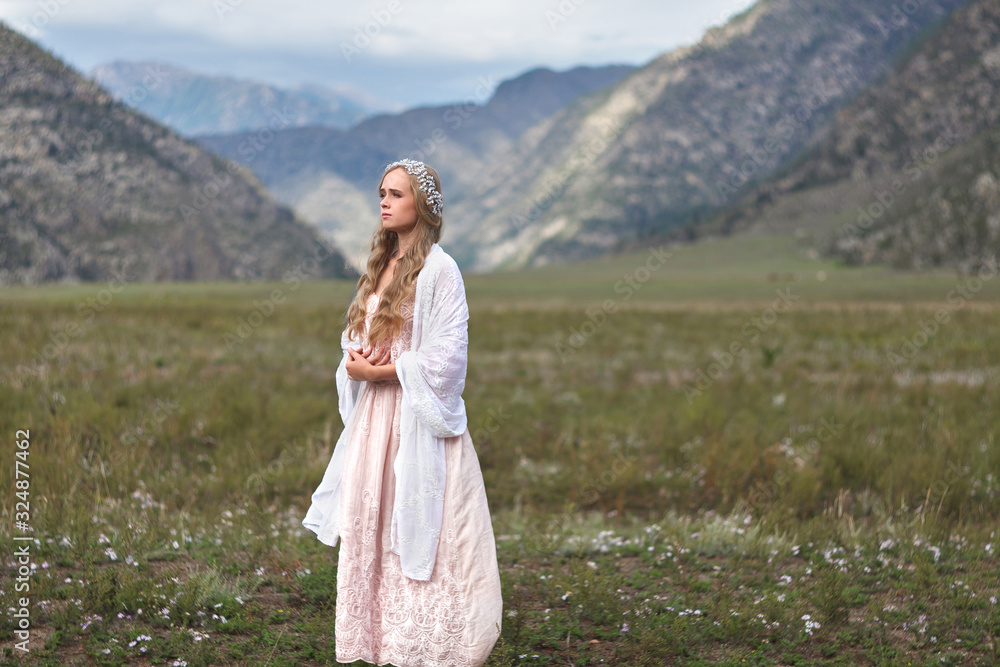 A girl walks through the meadow against the backdrop of the mountains. Prayer. A girl walks through the meadow against the backdrop of the mountains. Prayer.