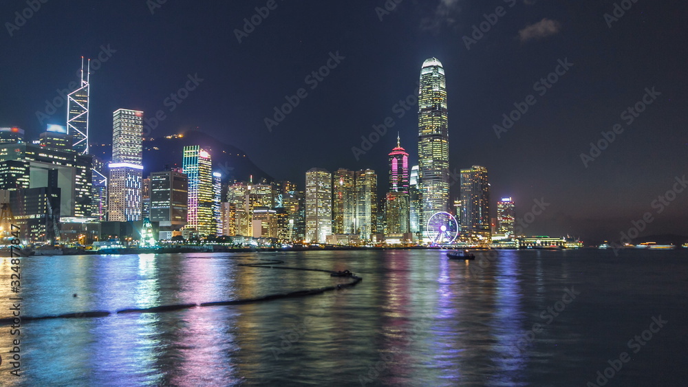 Hong Kong, China skyline panorama with skyscrapers at night from across Victoria Harbor timelapse.