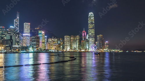 Hong Kong, China skyline panorama with skyscrapers at night from across Victoria Harbor timelapse.