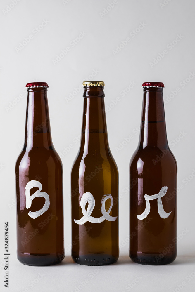 Front view three bottles of beer aligned on table Front view three bottles of beer aligned on table