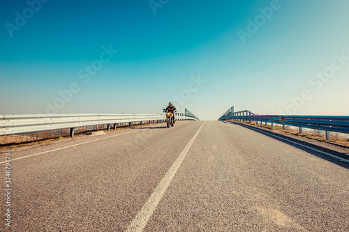 solo motorbiker driving on an empty road  - single man trip with his motorbike